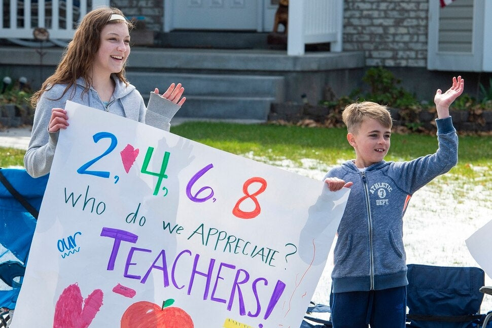Two kids holding up a sign for teachers during school closures
